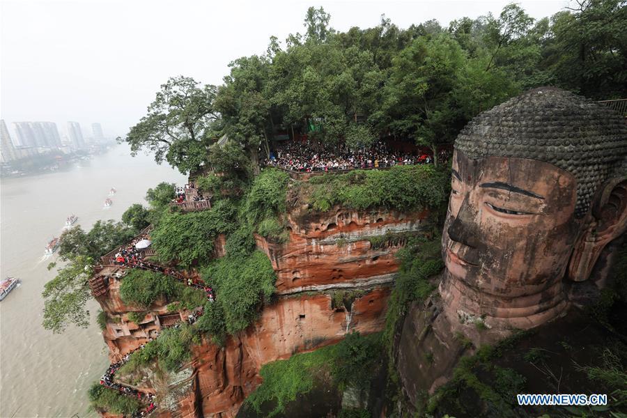 People view the statue of the Leshan Giant Buddha in Leshan City, southwest China\'s Sichuan Province, Oct. 4, 2018. The Leshan Buddha scenic area received about 43,800 visitors on the fourth day of China\'s National Day holiday. (Xinhua/Jiang Hongjing)