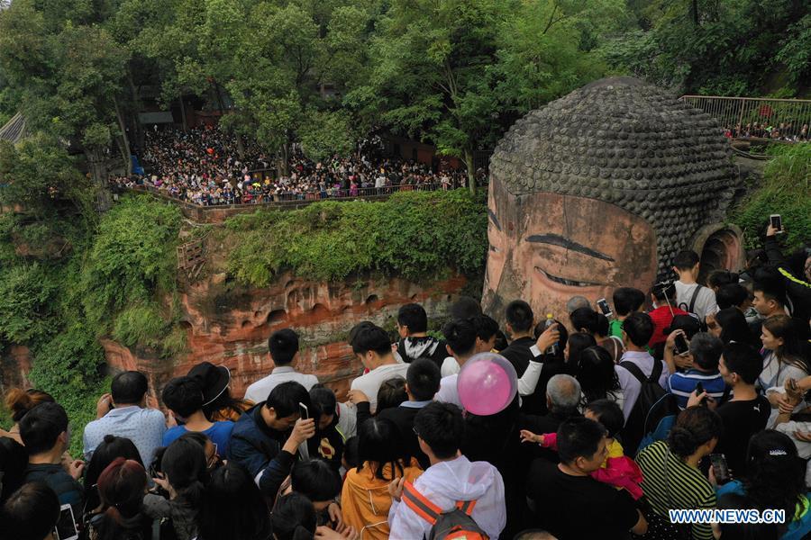 People view the statue of the Leshan Giant Buddha in Leshan City, southwest China\'s Sichuan Province, Oct. 4, 2018. The Leshan Buddha scenic area received about 43,800 visitors on the fourth day of China\'s National Day holiday. (Xinhua/Jiang Hongjing)