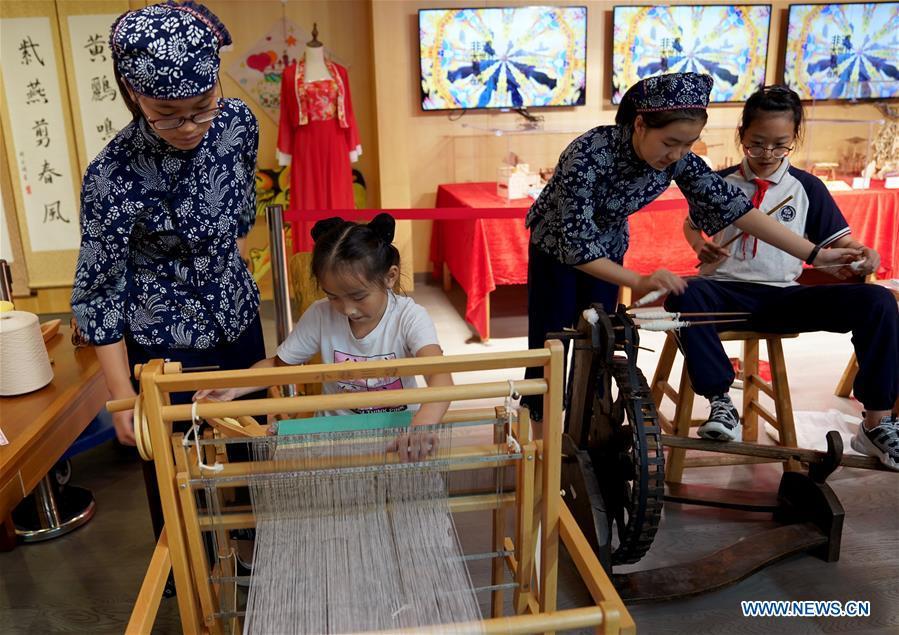 Pupils learn to operate the traditional shuttle loom in Shanghai, east China, Sept. 21, 2018. A series of activities were held in the Shanghai Big World on Sept. 21 to show young people\'s practice of intangible cultural heritages. (Xinhua/Liu Ying)