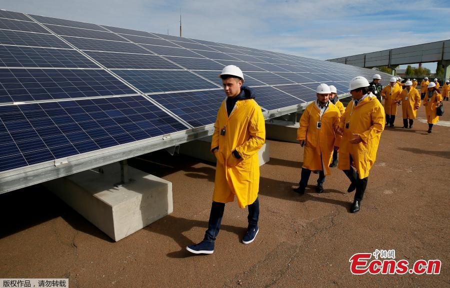Visitors walk by the photovoltaic panels during an official opening ceremony of the new one-megawatt solar power plant \'\'Solar Chernobyl\