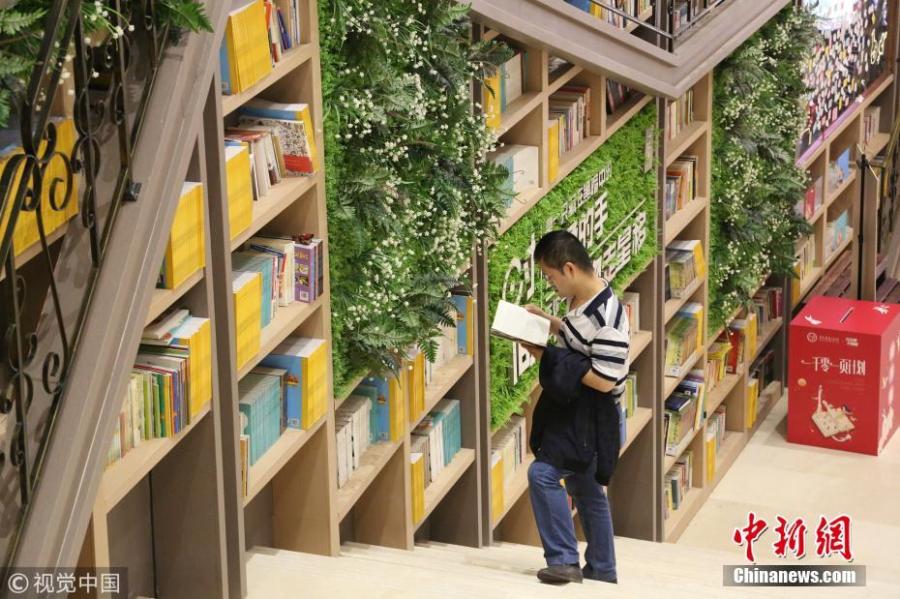 Tens of thousands of books are placed on shelves to form a 10-meter-tall books wall inside a shopping center in Chongqing, Oct. 10, 2018. (Photo/VCG)