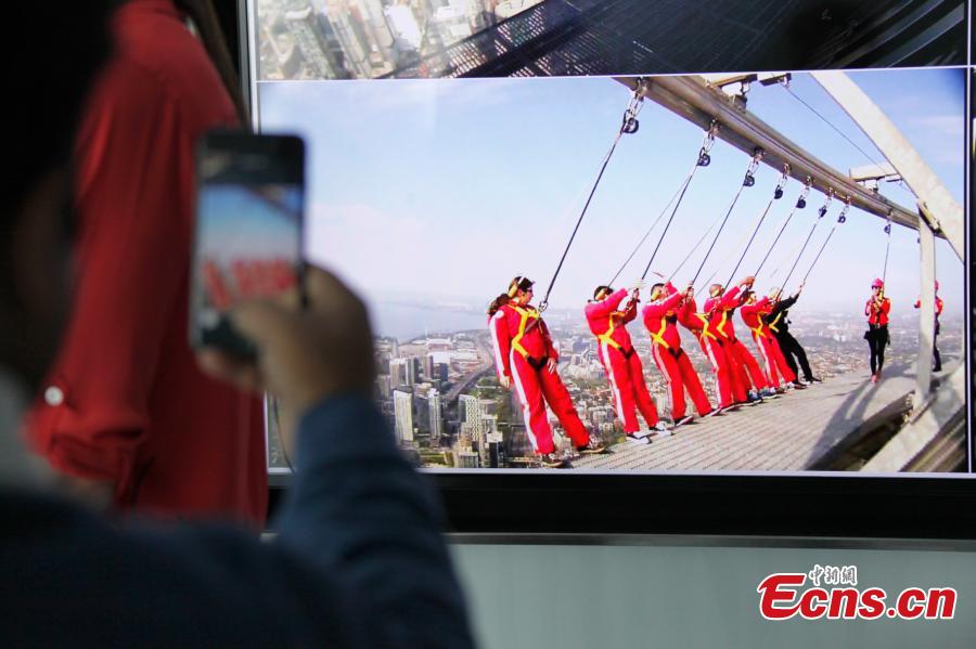A relative takes photos of the live broadcast of six new Canadians who take their oath of citizenship while harnessed on the CN Tower\'s \