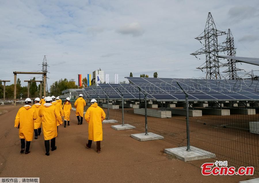 Visitors walk by the photovoltaic panels during an official opening ceremony of the new one-megawatt solar power plant \'\'Solar Chernobyl\