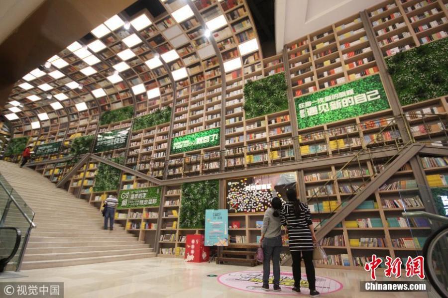 Tens of thousands of books are placed on shelves to form a 10-meter-tall books wall inside a shopping center in Chongqing, Oct. 10, 2018. (Photo/VCG)