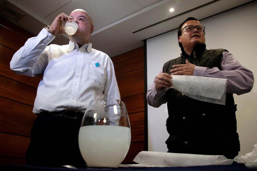 Chilean entrepreneur Roberto Astete (left) stands with Olivares and drinks a solution of water and dissolved PVA to prove it is safe to consume the mixture. (CLAUDIO REYES/FOR CHINA DAILY)