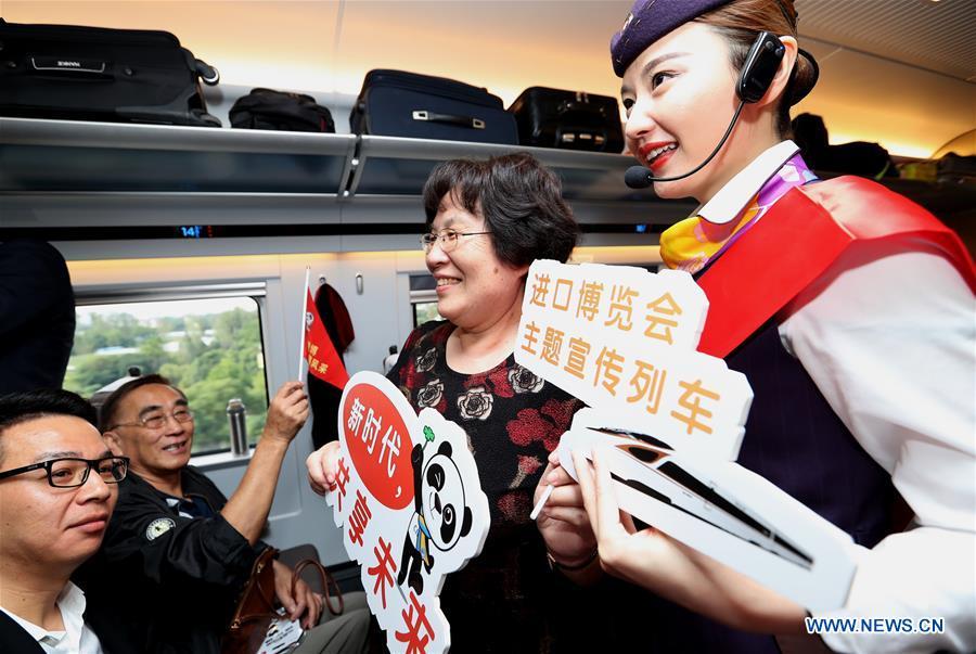 A railway attendant briefs passengers on information about the first China International Import Expo (CIIE) on board the G2 bullet train in east China\'s Shanghai, Oct. 10, 2018. Railway authorities have launched a campaign on Wednesday to promote the upcoming first CIIE on bullet trains running on the Beijing-Shanghai high-speed railway. (Xinhua/Chen Fei)