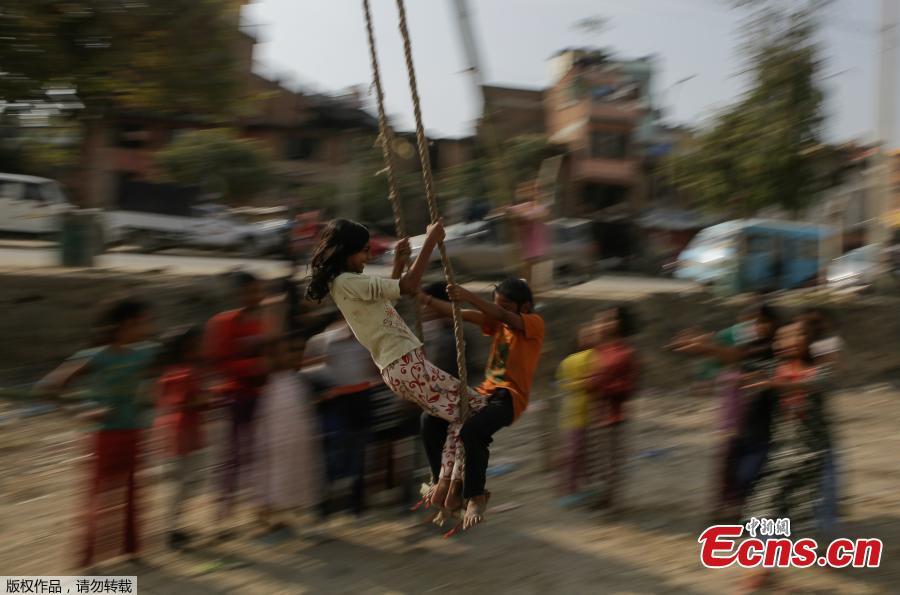 Two children play on a swing, popularly known as the \'Dashain Ping\', ahead of the Hindu festival of Dashain in Kathmandu, Nepal, Oct. 11, 2018. People of all ages often play on a swing in towns and villages during the celiebration of the festival. (Photo: China News Service/Pu Ladan)