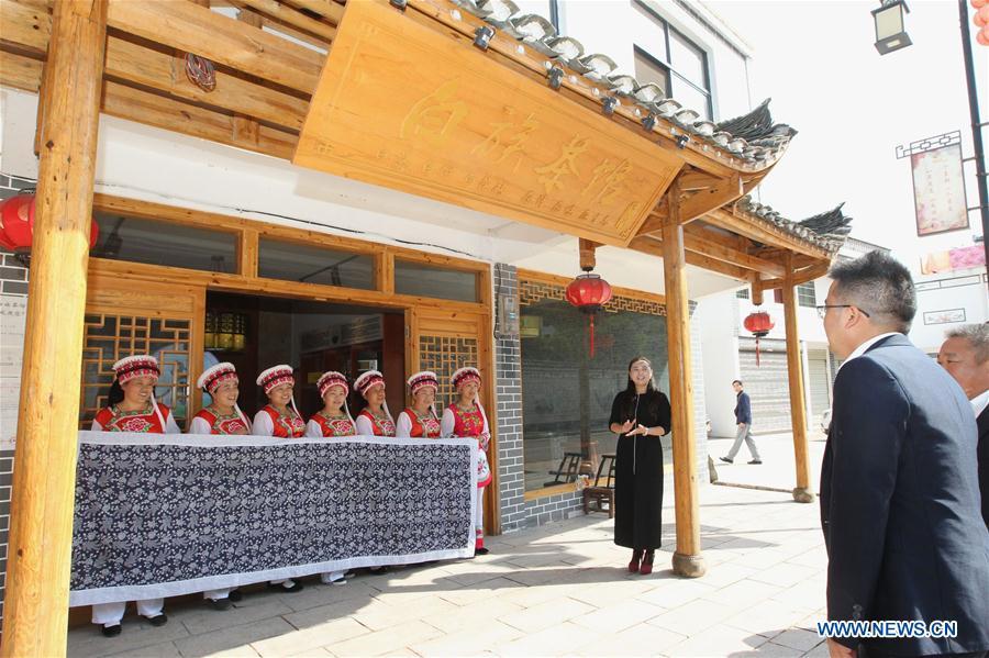 A guest is welcomed by women of Bai ethnic group at the door of a tea house at the Suoziqiu Village of Mahekou Township in Sangzhi County of Zhangjiajie City, central China\'s Hunan Province, Oct. 11, 2018. People of the Bai ethnic group here still follow the welcoming tradition of their immigrated ancestors to offer \