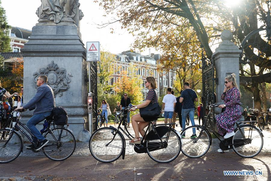 People ride bicycles on a street in Amsterdam, the Netherlands, Oct. 13, 2018. (Xinhua/Zheng Huansong)
