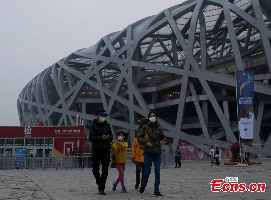 Tourists visit the area around National Stadium, also known as the Bird\'s Nest, on a smoggy day in Beijing, Oct. 14, 2018. Serious air pollution was reported in Beijing on Sunday. (Photo: China News Service/Liu Guanguan)