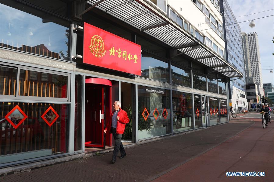 A man walks past a Chinese medicine store at the Chinatown in The Hague, the Netherlands, on Oct. 15, 2018. The Hague\'s Chinatown is located in the downtown area of the city. With red lanterns, Chinese restaurants, Chinese medicine service shops and other shops featuring Chinese culture, the street attracts many citizens and worldwide tourists. (Xinhua/Zheng Huansong)