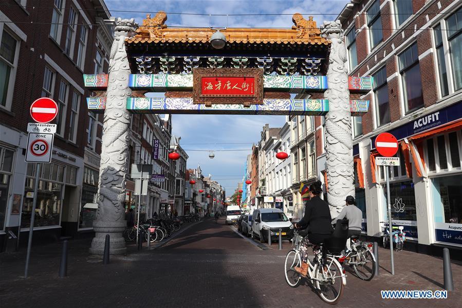 People ride bikes through the traditional Chinese archway at the Chinatown in The Hague, the Netherlands, on Oct. 15, 2018. The Hague\'s Chinatown is located in the downtown area of the city. With red lanterns, Chinese restaurants, Chinese medicine service shops and other shops featuring Chinese culture, the street attracts many citizens and worldwide tourists. (Xinhua/Zheng Huansong)