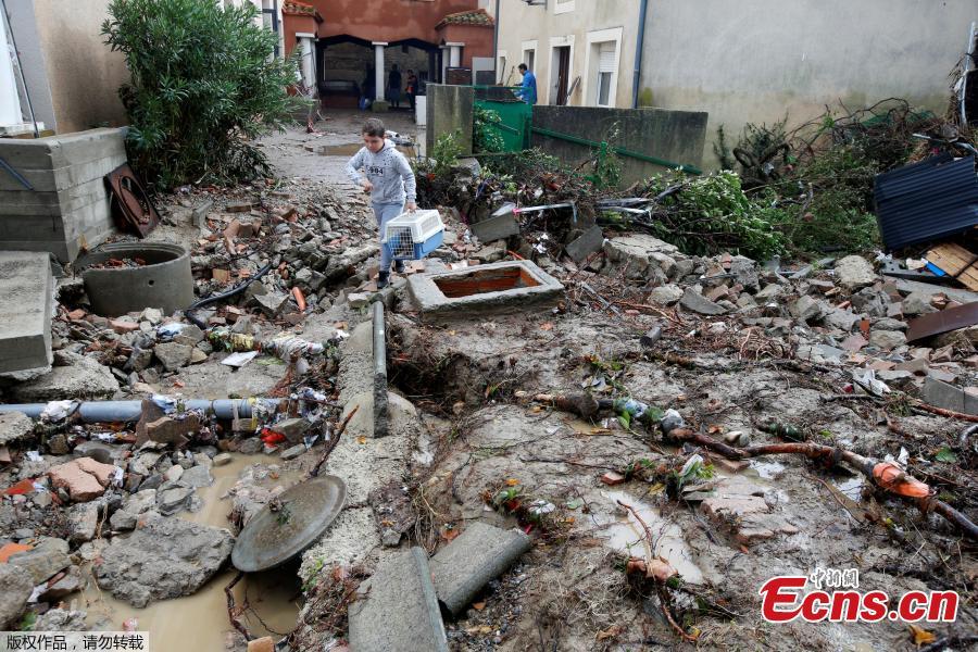 A child carries an animal in its cage on a rubble-strewn street as clean-up operations continue the day after some of the worst flash floods in a century turned rivers into raging torrents that engulfed homes and swept away cars hit the southwestern Aude district of France, in Conques, France, Oct. 16, 2018. At least 12 people died. (Photo/Agencies)