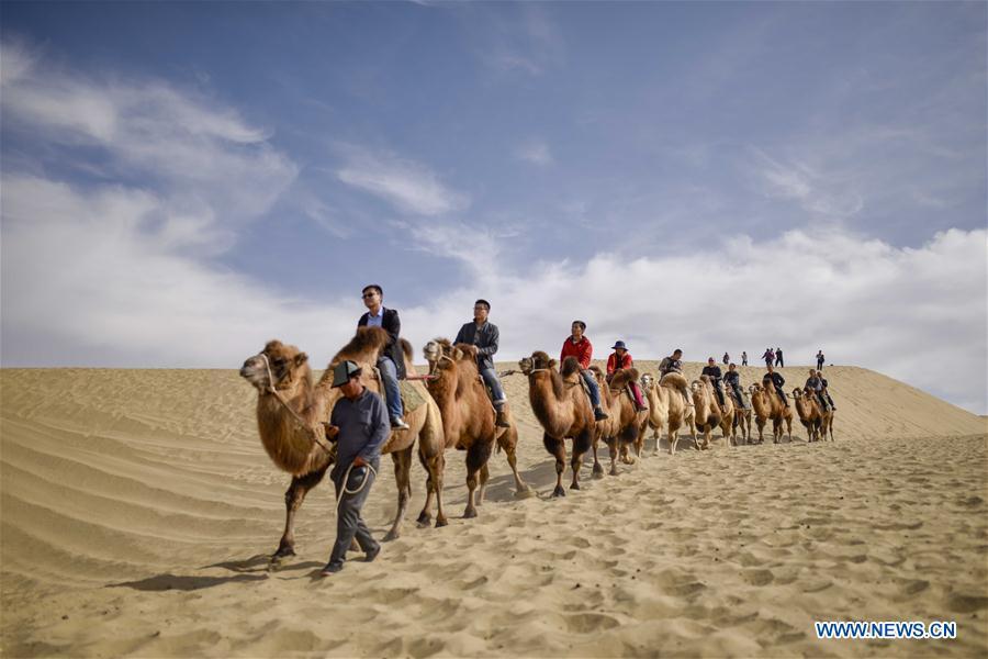 Tourists ride camels in Lop Nur People Village of Yuli County, northwest China\'s Xinjiang Uygur Autonomous Region, Oct. 16, 2018. The Lop Nur people depended basically on fishing for livelihood and developed a distinct culture based on their special lifestyle. Located in Tarim basin, Yuli is known for its natural scenery and ethnic culture and keeps attracting numerous tourists from at home and abroad. From Oct. 1 to 16, 2018, Yuli County has received more than 230,000 visitors, with a year-on-year increase of 31.46 percent. (Xinhua/Zhao Ge)
