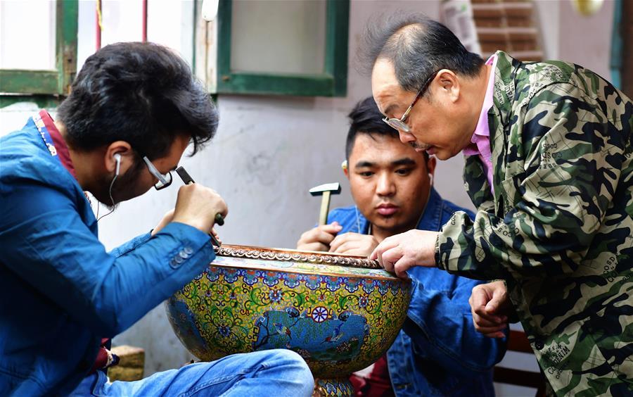 Lin Hui instructs workers on an enamelwork in Putian, southeast China\'s Fujian Province, Oct. 18, 2018. Lin Hui is an intangible cultural heritage inheritor of Lin\'s cloisonne, or copper padding thread weaving enamel, a kind of traditional Chinese handicrafts. (Xinhua/Wei Peiquan)