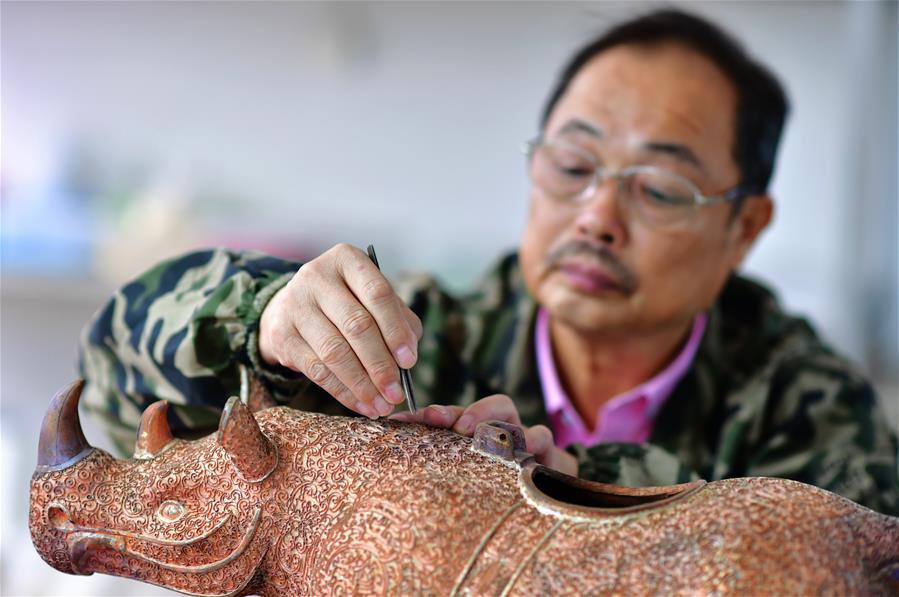 Lin Hui works on an enamel rhino in Putian, southeast China\'s Fujian Province, Oct. 18, 2018. Lin Hui is an intangible cultural heritage inheritor of Lin\'s cloisonne, or copper padding thread weaving enamel, a kind of traditional Chinese handicrafts. (Xinhua/Wei Peiquan)