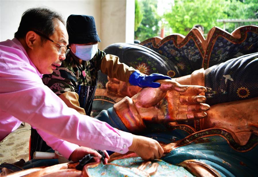 Lin Hui instructs workers on polishing enamelworks in Putian, southeast China\'s Fujian Province, Oct. 18, 2018. Lin Hui is an intangible cultural heritage inheritor of Lin\'s cloisonne, or copper padding thread weaving enamel, a kind of traditional Chinese handicrafts. (Xinhua/Wei Peiquan)