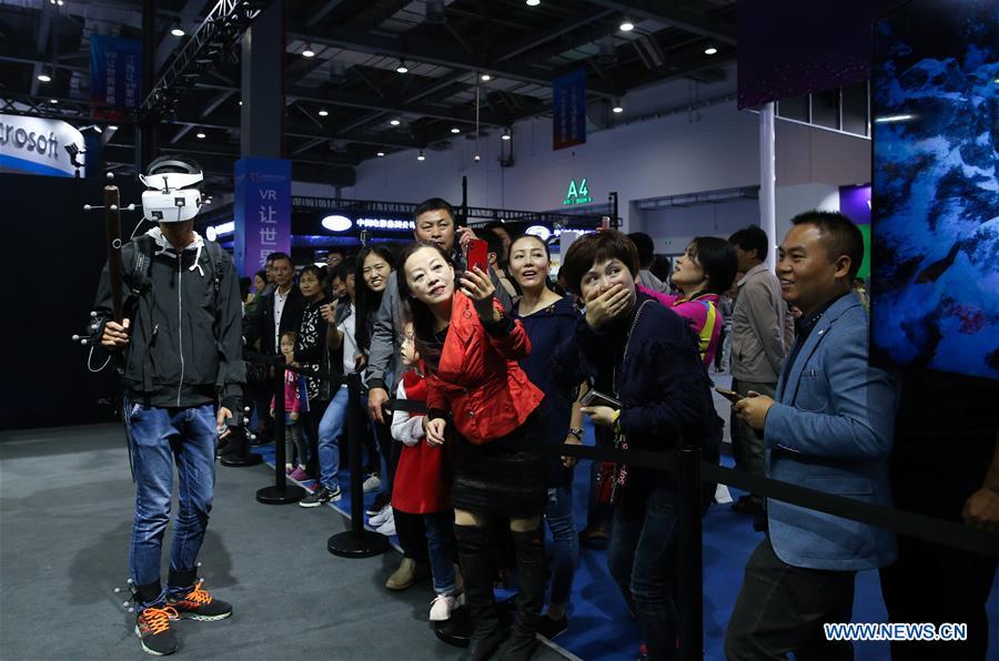 A visitor (L) plays VR (virtual reality) game during the 2018 World Conference on VR Industry in Nanchang, east China\'s Jiangxi Province, Oct. 19, 2018. The 2018 World Conference on VR Industry opened here on Friday. The three-day event attracts more than 150 global exhibitors in the virtual reality field. (Xinhua/Pan Siwei)