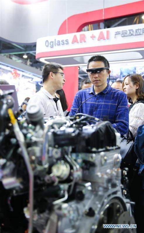 A visitor (2nd R) learns about car motor assembling via a pair of AR (augmented reality) glasses during the 2018 World Conference on VR Industry in Nanchang, east China\'s Jiangxi Province, Oct. 19, 2018. The 2018 World Conference on VR Industry opened here on Friday. The three-day event attracts more than 150 global exhibitors in the virtual reality field. (Xinhua/Pan Siwei)
