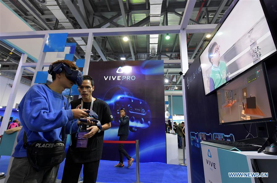 A visitor (L) tries a VR (virtual reality) device during the 2018 World Conference on VR Industry in Nanchang, east China\'s Jiangxi Province, Oct. 19, 2018. The 2018 World Conference on VR Industry opened here on Friday. The three-day event attracts more than 150 global exhibitors in the virtual reality field. (Xinhua/Peng Zhaozhi)