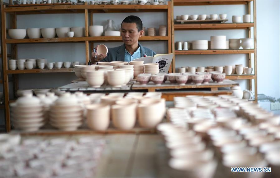 A craftsman named Zeng Lei counts a batch of finished eggshell porcelains in Jingdezhen, east China\'s Jiangxi Province, on Oct. 19, 2018. Eggshell porcelain, one of the traditional porcelains produced in \