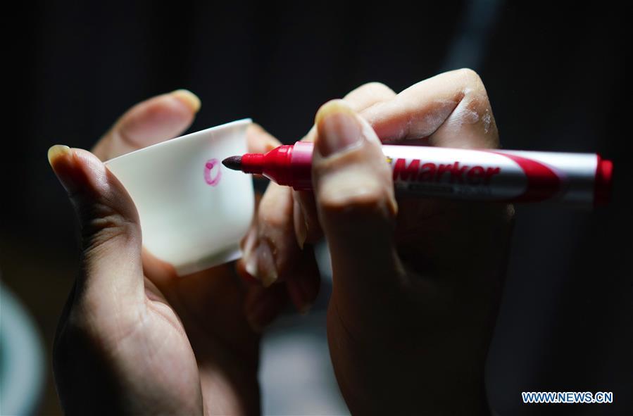 A craftsman named Wang Minhui makes a mark on the body of an unqualified finished eggshell porcelain in Jingdezhen, east China\'s Jiangxi Province, on Oct. 19, 2018. Eggshell porcelain, one of the traditional porcelains produced in \