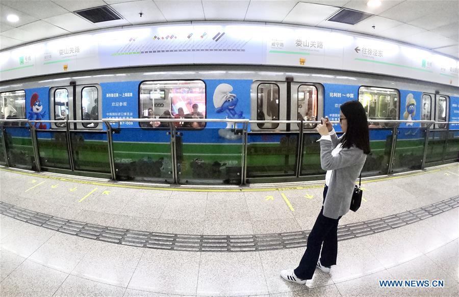 A passenger takes photos of a China-Belgium theme train of Shanghai Metro Line 2 bearing character images from Belgian comic \