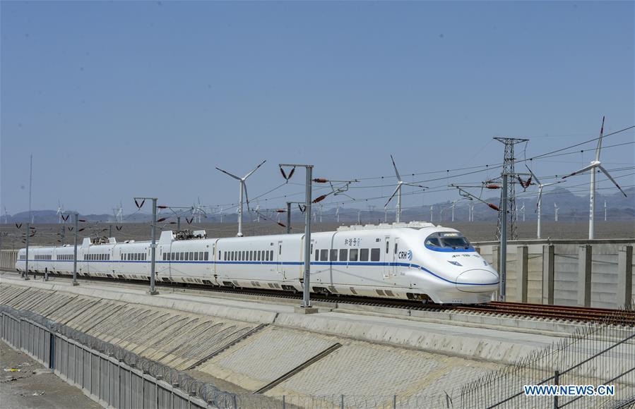 A bullet train runs past a wind power plant in Urumqi, northwest China\'s Xinjiang Uygur Autonomous Region, May 29, 2014. Xinjiang has seen a surge in the electricity generation from clean energy. According to State Grid Xinjiang Electric Power Co., Ltd., wind and solar power generated 27.81 billion and 9.07 billion kilowatt hours (kwh) of electricity, respectively, in the first nine months of 2018 in the region. With abundant wind and solar resources, Xinjiang is a pioneer in using new energy in China, with installed new-energy capacity having exceeded 27 million kilowatts so far. (Xinhua/Zhao Ge)