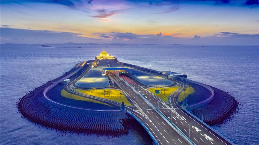 An engineer introduces construction of artificial islands for the HZMB. (Photo provided to China Daily)

5. Length, tunnel and artificial islands

HZMB is a 55-kilometer-long bridge-island-tunnel complex across the Pearl River Estuary. It is the world\'s longest sea crossing. The bridge consists of a 6.7-km undersea tunnel, which is the country\'s first offshore immersed tunnel and the world\'s longest immersed tunnel for road traffic. It is connected to the bridge through two offshore artificial islands.

The tunnel is built to reserve room for a planned shipping channel for passenger liners with a displacement of 300,000 tons. As the planned location is close to the Hong Kong International Airport, where there is height limitation in the airspace, a tunnel must be built subsea instead of a bridge with tall towers.