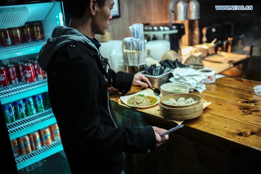 A man picks up his food in Shaxian Snacks restaurant in Brooklyn, New York, the United States, on Oct. 21, 2018. China\'s restaurant chain serving Shaxian County cuisine has opened its first eatery in the United States. Located at 818, 60th St. Brooklyn, the restaurant, which opened Monday, presents overseas foodies with traditional Chinese snacks, including peanut butter noodles and pork wontons. (Xinhua/Li Muzi)