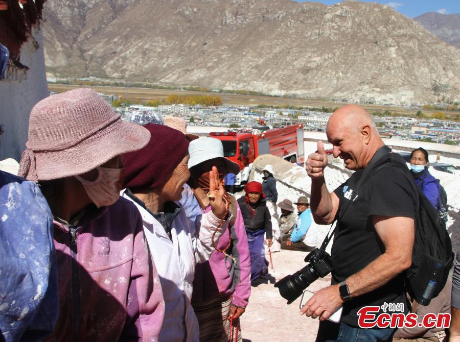 A tourist from the United States greets pilgrims to the Potala Palace in Lhasa, Southwest China’s Tibet Autonomous Region, Oct. 23, 2018. The painting work will take one week. (Photo: China News Service/Zhao yan)