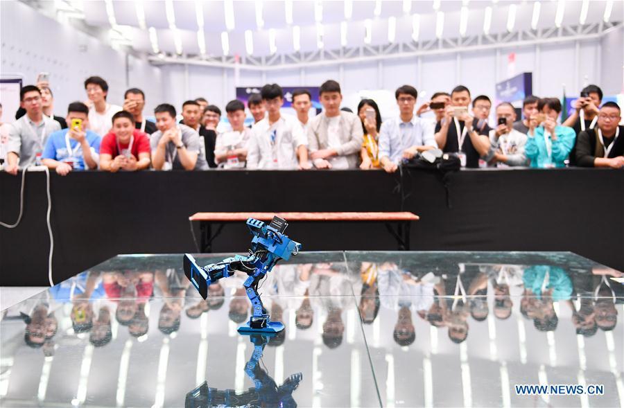 Visitors watch a humanoid robot dancing at the 20th National Robot and Artificial Intelligence Competition in Shunde District of Foshan, south China\'s Guangdong Province, Oct. 24, 2018. The 20th National Robot and Artificial Intelligence Competition kicked off here on Wednesday. More than 200 teams from 78 Chinese colleges will take part in 49 competitions under 13 categories. (Xinhua/Liu Dawei)