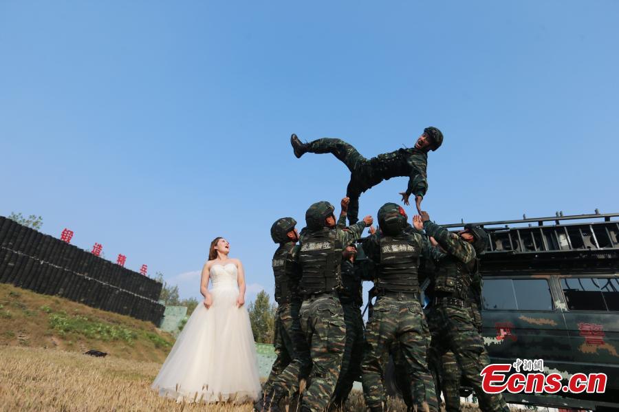 An armed police squad head in Yantai City, East China’s Shandong Province and his wife took special wedding photos at a barrack amid cheers and support of other members of the paramilitary police unit. (Photo: China News Service/Yang Lei)