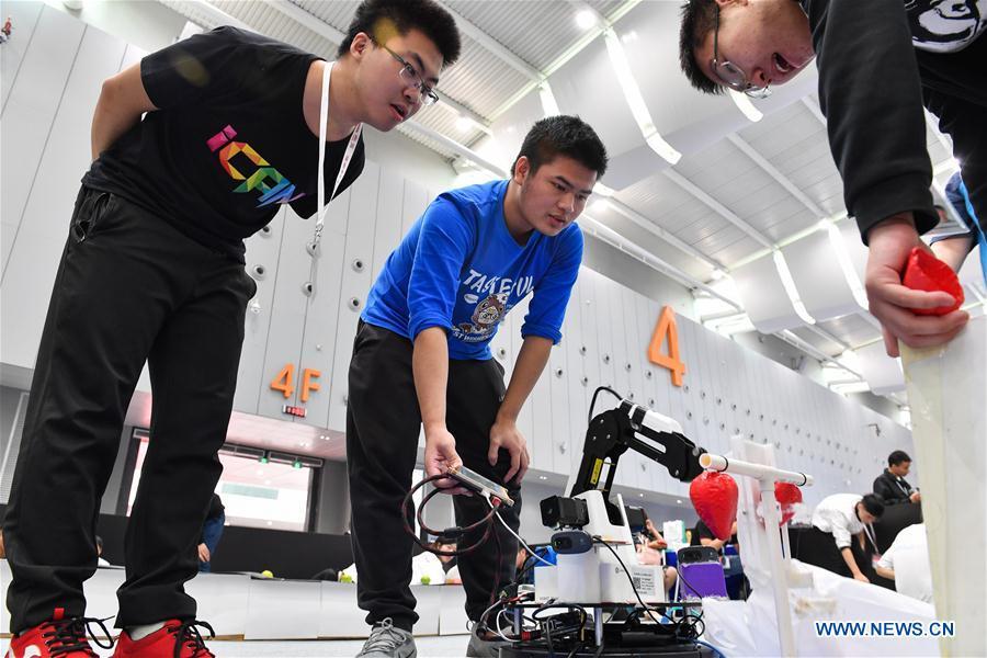 Lao Guihong (C) from Dalian University of Technology adjusts a robot designed for picking at the 20th National Robot and Artificial Intelligence Competition in Shunde District of Foshan, south China\'s Guangdong Province, Oct. 24, 2018. The 20th National Robot and Artificial Intelligence Competition kicked off here on Wednesday. More than 200 teams from 78 Chinese colleges will take part in 49 competitions under 13 categories. (Xinhua/Chen Liqun)
