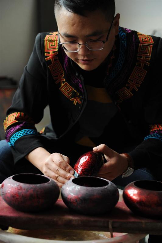 Gao burnishes the lid of a lacquer pot to bring the surface to the highest sheen. (Photo/Xinhua)