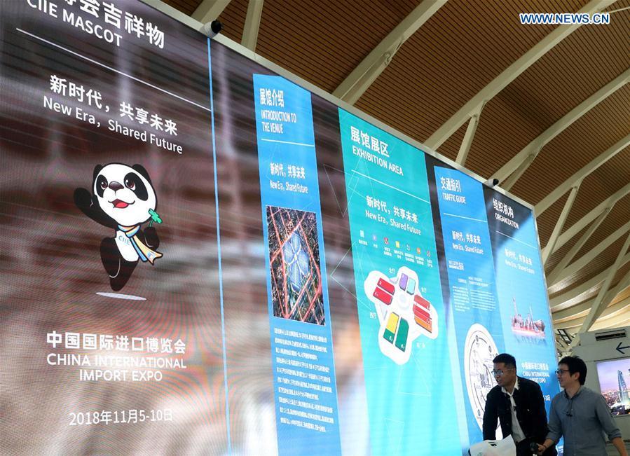 Passengers walk passing a LED screen playing promotion videos for the first China International Import Expo (CIIE) at Pudong International Airport in Shanghai, east China, Oct. 25, 2018. The CIIE will be held in Shanghai on Nov. 5-10. (Xinhua/Chen Fei)