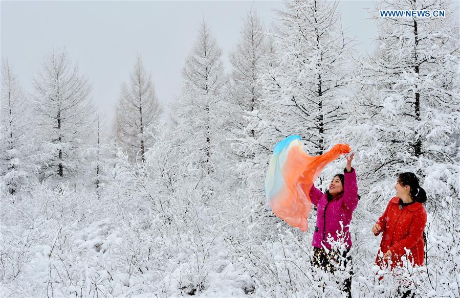 People enjoy the snow scenery at a scenic spot in Oroqen Autonomous Banner of Hulun Buir, north China\'s Inner Mongolia Autonomous Region, Oct. 26, 2018. A snowfall hit Oroqen Autonomous Banner of Hulun Buir on Friday.(Xinhua/Hou Yupeng)