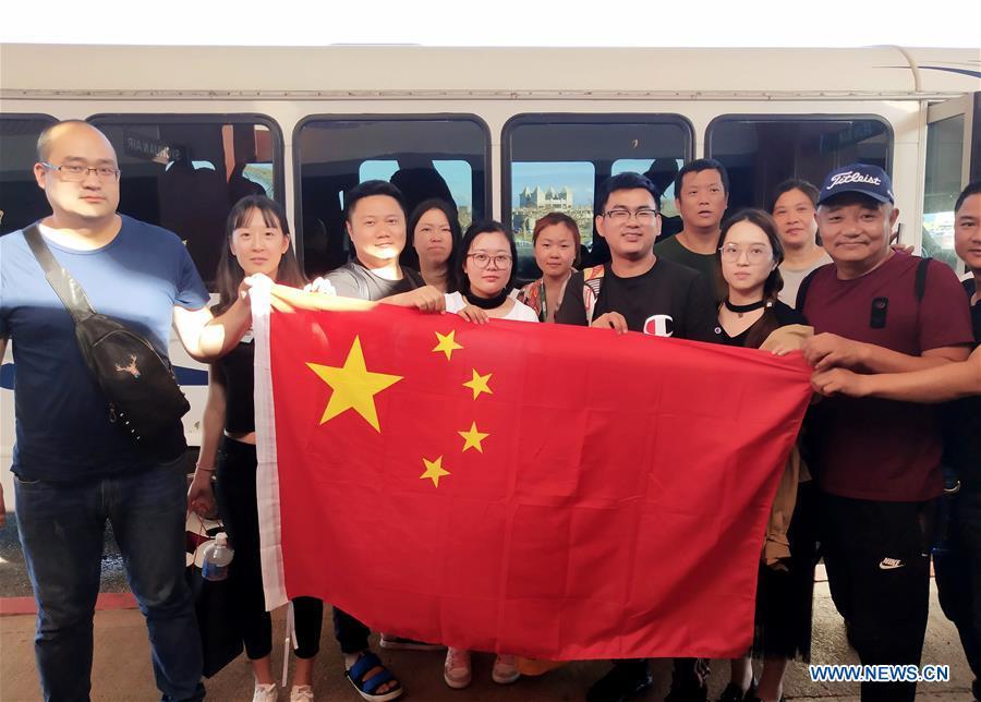 Chinese tourists pose with Chinese national flag before starting to fly back home in Saipan, the Commonwealth of the Northern Mariana Islands (CNMI), Oct. 28, 2018. Some 1,500 Chinese tourists trapped in Saipan by Super Typhoon Yutu started to fly back home on Sunday. (Xinhua)