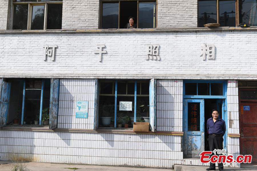 Photographer Wei Jixiong poses for a photo at the Agan Photo Studio in Lanzhou City, Northwest China’s Gansu Province, Oct. 27, 2018. Since Wei began working at the studio in the 1970s, he has continually used film cameras to take photos for customers despite the popularity of digital cameras. (Photo: China News Service/Yang Yanmin)