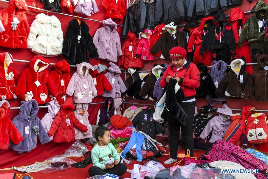 A vender sells clothes at a Sunday bazaar in Bachu County, northwest China\'s Xinjiang Uygur Autonomous Region, Oct. 28, 2018. (Xinhua/Hu Huhu)