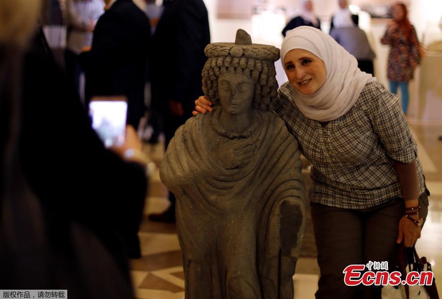 A woman poses for a picture with a restored sculpture, displayed in an exhibition, at the Opera house in Damascus, Syria October 3, 2018. Picture taken October 3, 2018. (Photo/Agencies)