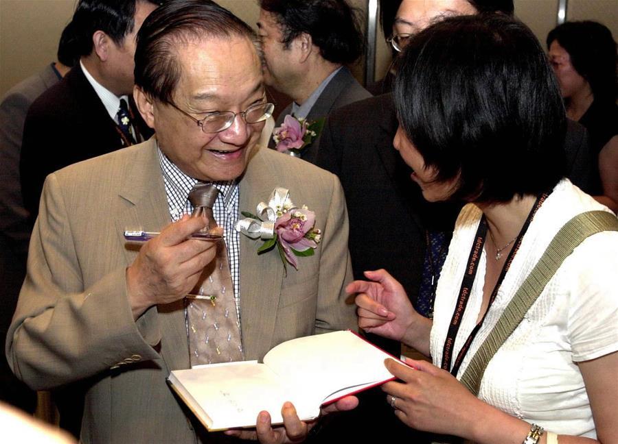 In this file photo, Jin Yong (L) signs a book for a reader during Hong Kong Book Fair in Hong Kong, south China, on July 22, 2001. Famous Chinese martial arts novelist Louis Cha Leung-yung, more widely known by his pen name Jin Yong, died at 94 at a hospital in Hong Kong on Tuesday. Cha created many widespread martial arts novels between 1955 and 1972. Cha, who also co-founded the Hong Kong daily newspaper Ming Pao, has been regarded as one of the greatest and most popular martial arts writers. (Xinhua/Shen Qiao)