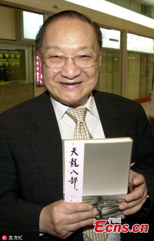 Chinese martial arts novelist Louis Cha holds one of his popular novels Demi-Gods and Semi-Devils upon his arrival at an airport in Taiwan, Sept. 19, 2005. (Photo/IC)