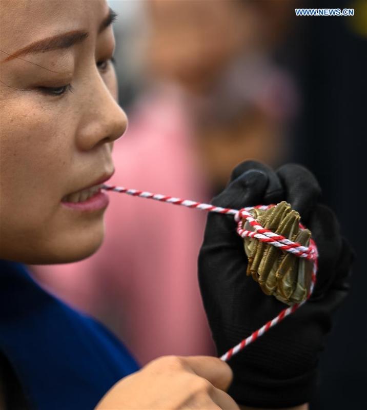 A woman takes part in a crab binding contest in Sihong County, east China\'s Jiangsu Province, Nov. 3, 2018. A total of 100 contestants participated in the event on Saturday. The winner bound 30 crabs within 3 minutes and 59 seconds. (Xinhua/Li Xiang)