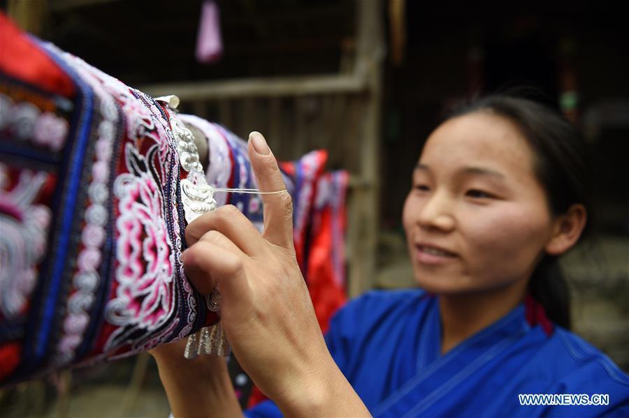 Yang Xinghe embroiders Miao costumes at Xinjiang Village in Taijiang County of Qiandongnan Miao and Dong Autonomous Prefecture, southwest China\'s Guizhou Province, on Nov. 4, 2018. Born with hearing loss, Yang Xinghe, 28, is a female of the Miao ethnic group, who are engaged in Miao embroidery at the village. She learned embroidery from her mother when she was only a child, and has been a locally well-known master now. (Xinhua/Liu Kaifu)
