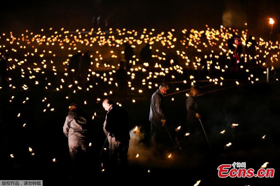 Volunteers light torches that are part of the installation \