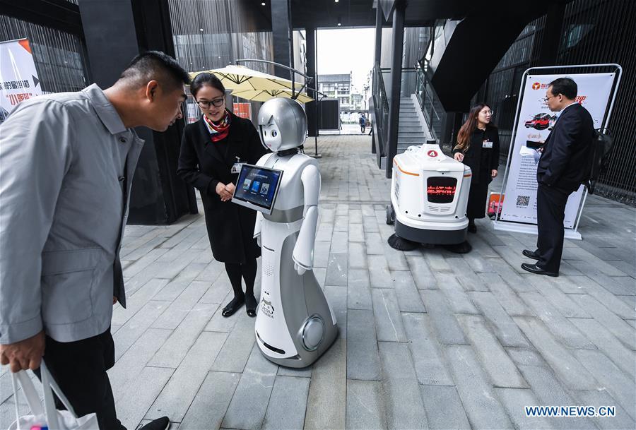 A visitor (L) interacts with a robot at the Light of Internet Expo of the fifth World Internet Conference in Wuzhen Township of Tongxiang, east China\'s Zhejiang Province, Nov. 6, 2018. Opening here on Tuesday, the exposition focuses on the world\'s most recent internet development trends and cutting-edge technologies, showing the latest internet technologies, achievements, products and applications of more than 430 enterprises and institutions from home and abroad. (Xinhua/Xu Yu)