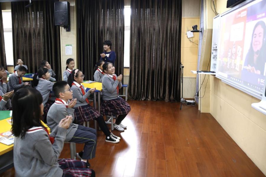 Students from Wuzhen Zhicai Primary School interact with a foreign teacher in Canada on a video call during an English class. (Photo/China Daily)