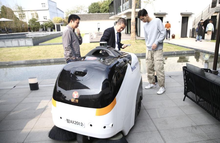 Visitors try out an intelligent cleaning machine at the Binzhi AI Hotel in Wuzhen. The hotel adopts an all-in-one tech platform that integrates guests, rooms, facilities and staff management. (Photo/China Daily)