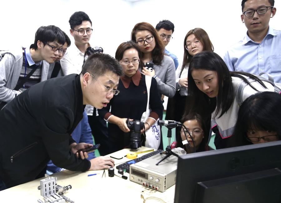 Yin Xiaodong (left), CEO of Jiaxing Yuguang Optoelectronic Technology Co, shows visitors how the Face ID feature of an iPhone X works with the help of an infrared camera at the company\'s office in Tongxiang Science and Technology Entrepreneurs Park, in Tongxiang, Zhejiang Province. [(Photo/China Daily)
The latest technological innovations have been applied in the town, now covering an area of 110 square kilometers from the previous 67 square km, with a better ecology and more complete infrastructure, luring internet professionals from around the world.
Among the latest technologies to be adopted are the 5G cellular network and internet hospitals, greatly improving convenience for the local residents.
For example, by the end of 2017, the Internet Hospital of Wuzhen has conducted over 12,000 remote medical consultations through the internet, making it a leading medical and health platform in the nation.
China Daily looks at some of the leading technological achievements and ways that the internet has reshaped the lives of locals in Wuzhen, Tongxiang and Jiaxing.